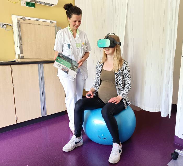 Obstetrieverpleegkundige Lotte Kroeze-Roolvink helpt een zwangere patiënt bij het gebruik van de VR-bril.