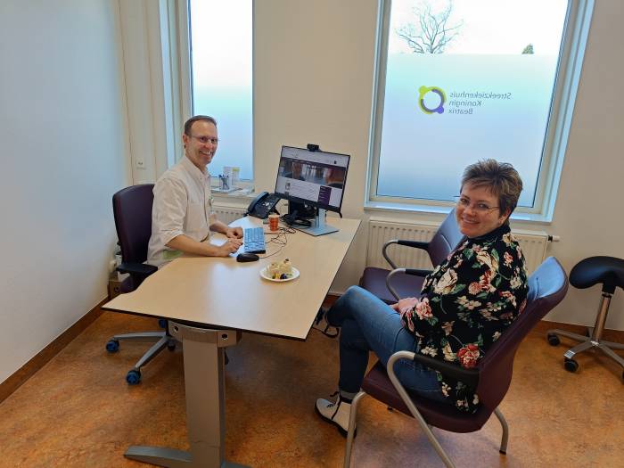 Reumatoloog Paul Olthof en polisecretaresse Kim Lubbers vieren de opening van de buitenpolikliniek in Ruurlo met een stukje taart. Zij verwelkomden daar vandaag de eerste patiënten.